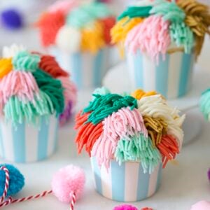 Multiple cute cupcakes with multi-colored frosting.