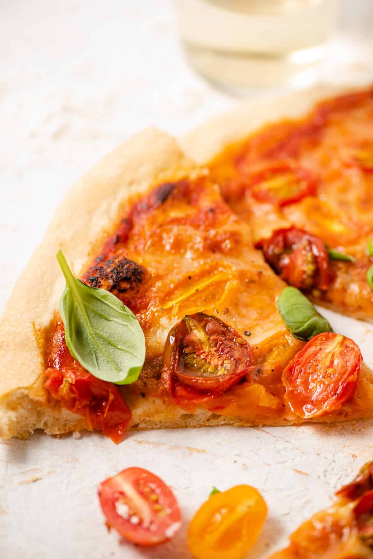 A close up of one slice of tomato pizza topped with fresh basil