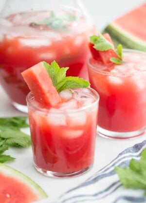 A couple glasses of watermelon agua fresca with a stick of watermelon and fresh mint.