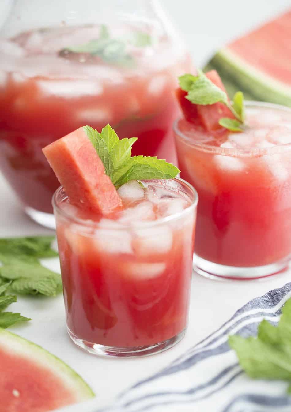 A couple glasses of watermelon agua fresca with a stick of watermelon and fresh mint.