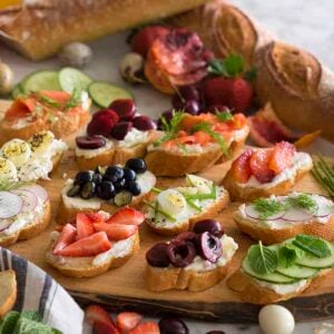 A group of canapés on a wooden board topped with various ingredients
