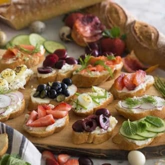 A group of canapés on a wooden board topped with various ingredients