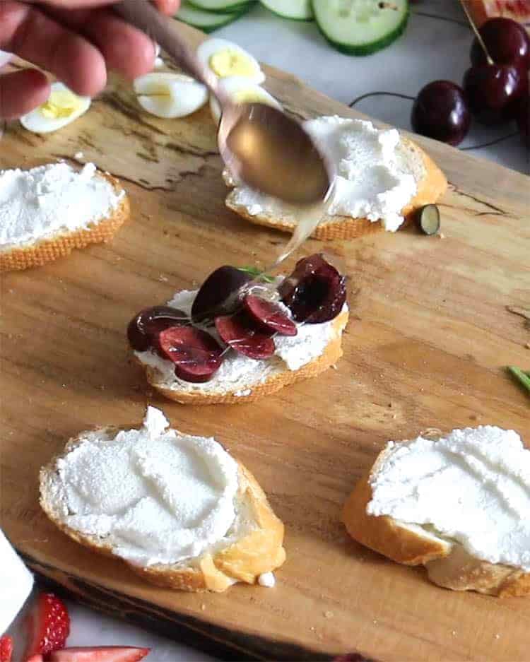 Cherries and honey being added to make a canapé.