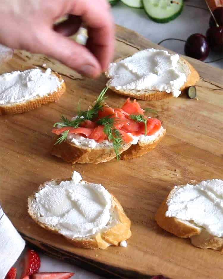 Smoked salmon and fresh dill being added to make a canapé.