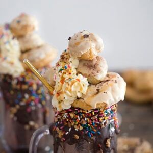 A photo of a freakshake topped with eclairs, creampuffs, whipped cream, chocolate, nuts and sprinkles.