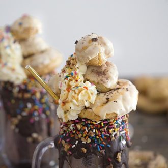 A photo of a freakshake topped with eclairs, creampuffs, whipped cream, chocolate, nuts and sprinkles.
