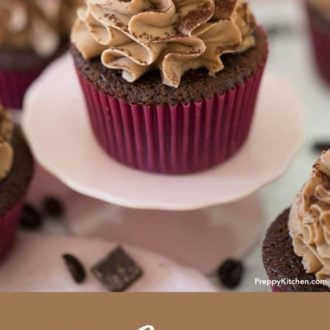 Chocolate cupcake with chocolate covered coffee bean on top sitting on a cupcake stand.