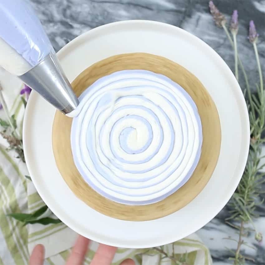 Picture of white and lavender Buttercream being piped onto a cake layer
