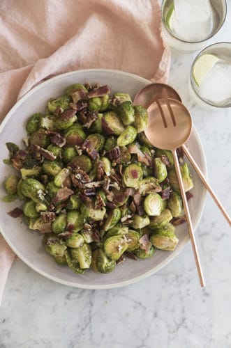 A photo of Brussel sprouts with bacon and caramelized pecans on a serving dish.