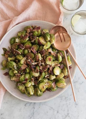 A photo of Brussel sprouts with bacon and caramelized pecans on a serving dish.