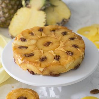 photo of pineapple upside down cake with pecans on a white cake platter