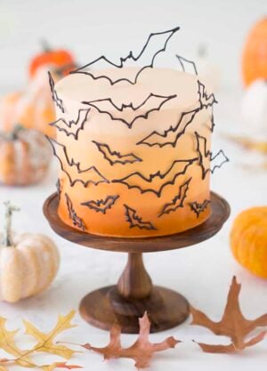 photo of an ombre orange cake covered in candy melt bats on a wooden cake stand