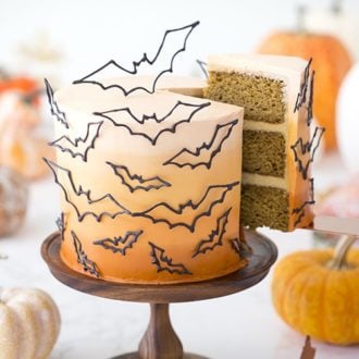 photo of a n ombre orange cake covered in candy melt bats with a piece being removed.