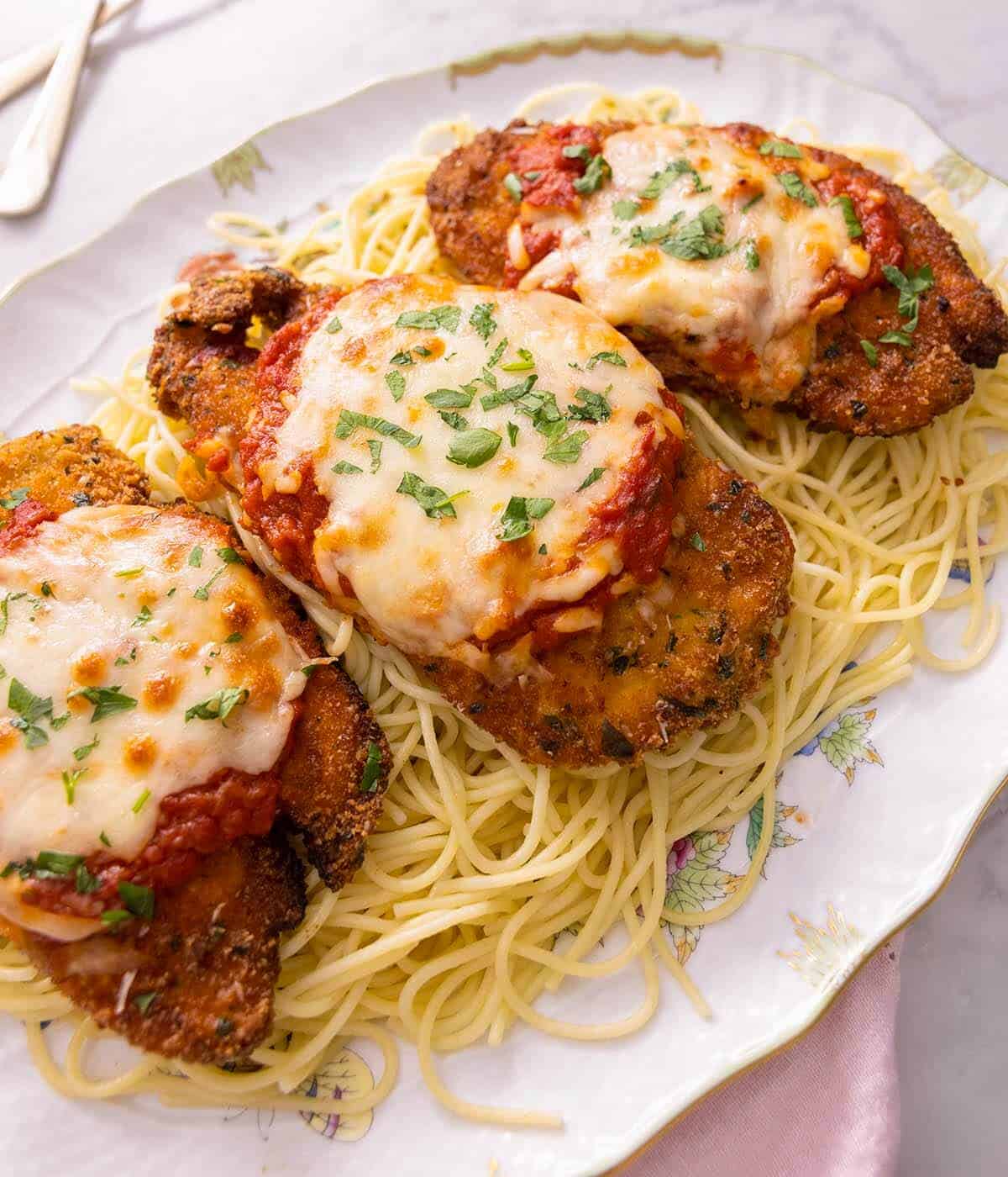 Three pieces of chicken parmesan on top of spaghetti