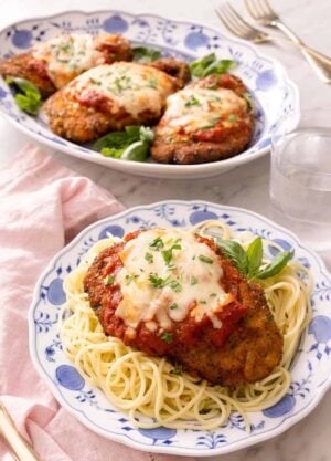 Chicken parmesan on a blue plate with spaghetti