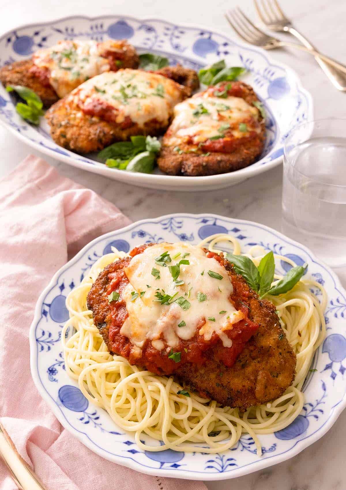 Chicken parmesan on a blue plate with spaghetti