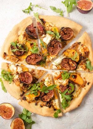 An overhead shot of a fig pizza cut into slices