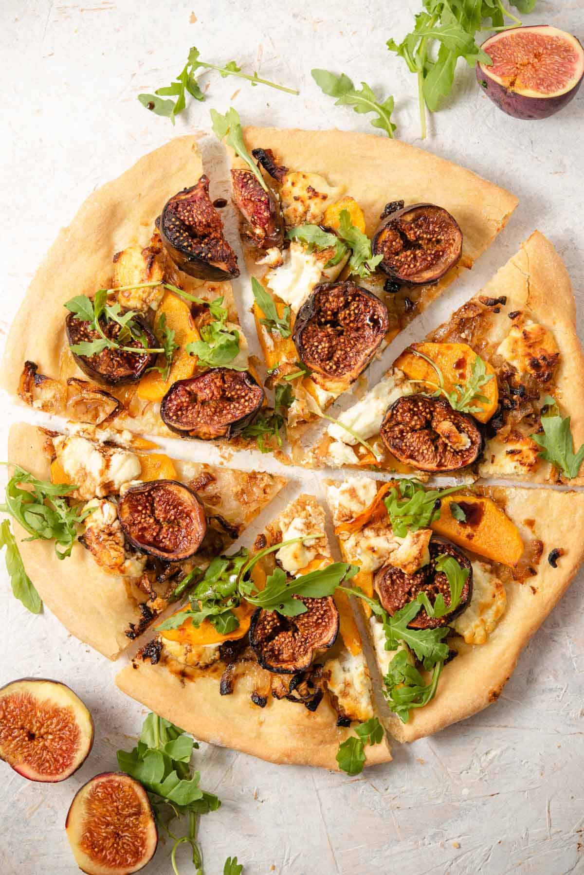 An overhead shot of a fig pizza cut into slices