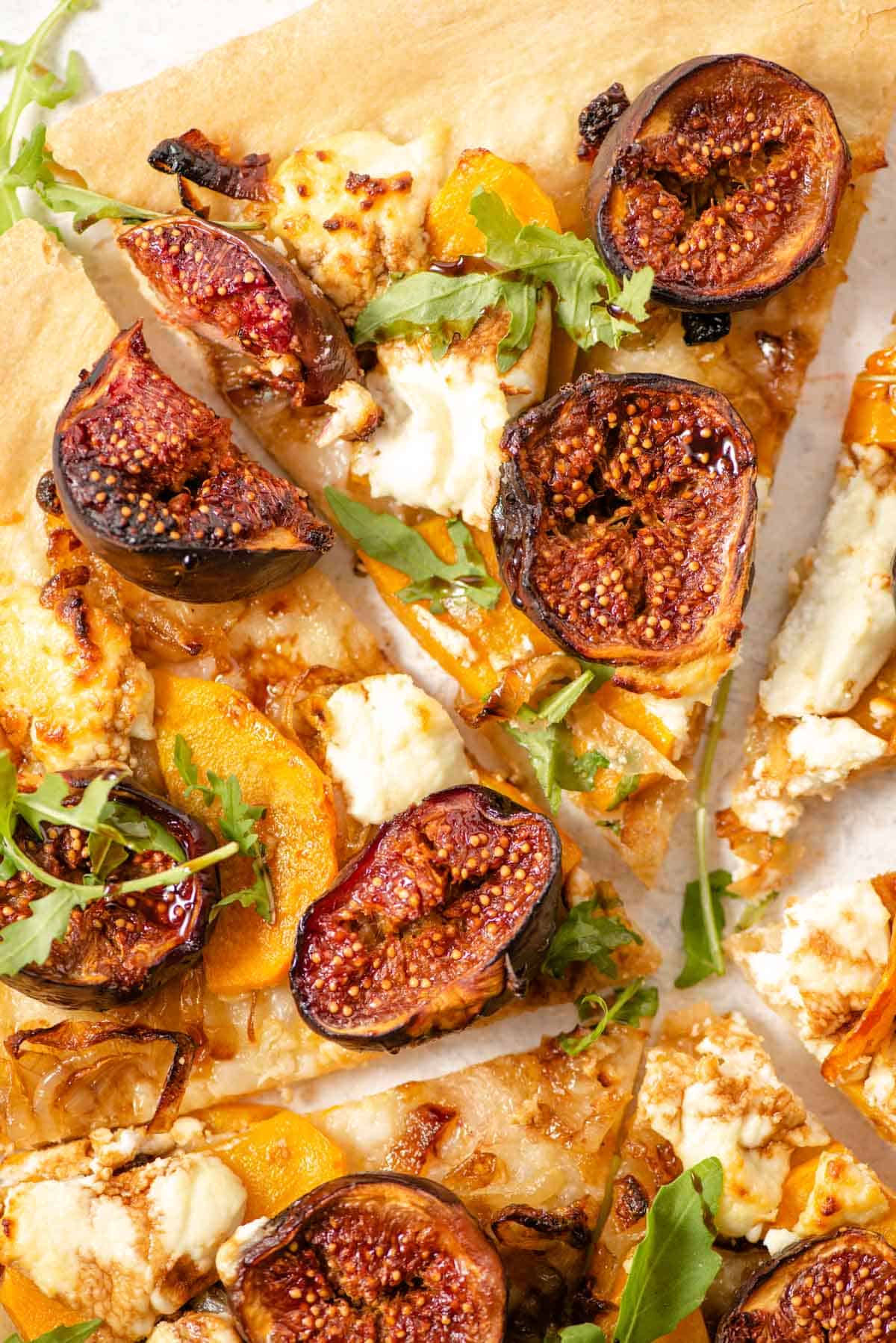 A close up of slices of pizza topped with figs and goats cheese