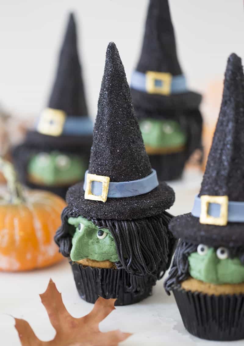 A photo of realistic looking witch cupcakes on a white table