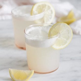 A photo of two gin fizz cocktails garnished with lemon wedges.
