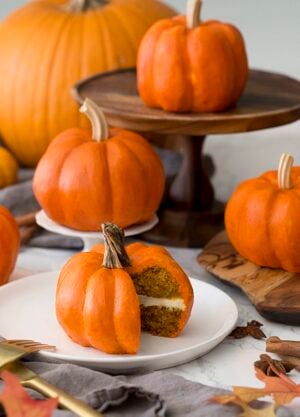 mini pumpkin cakes on a table with real pumpkins mixed in.
