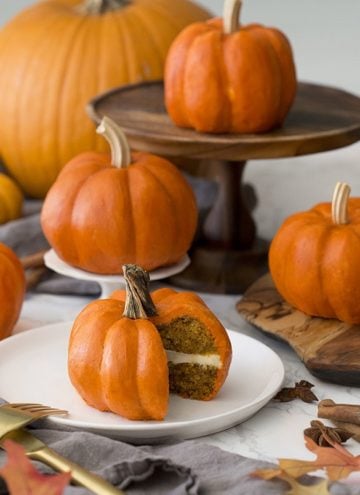 mini pumpkin cakes on a table with real pumpkins mixed in.
