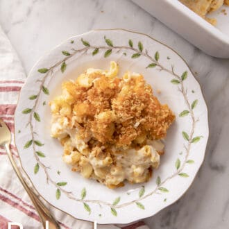 Baked mac and cheese with toasted breadcrumbs on a plate next to a white and red linen napkin.