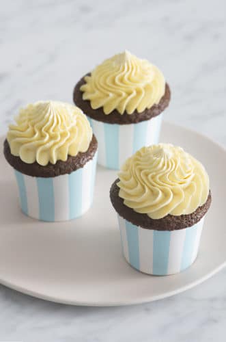 A photo of three chocolate cupcakes topped with dollops of french buttercream.
