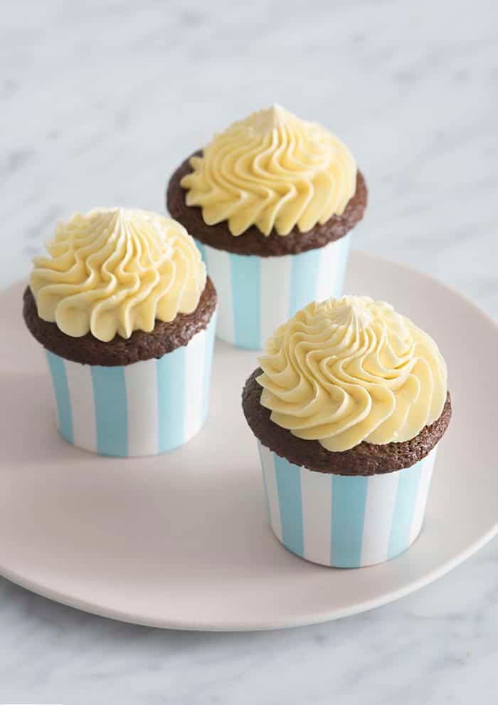 A photo of three chocolate cupcakes topped with dollops of french buttercream.