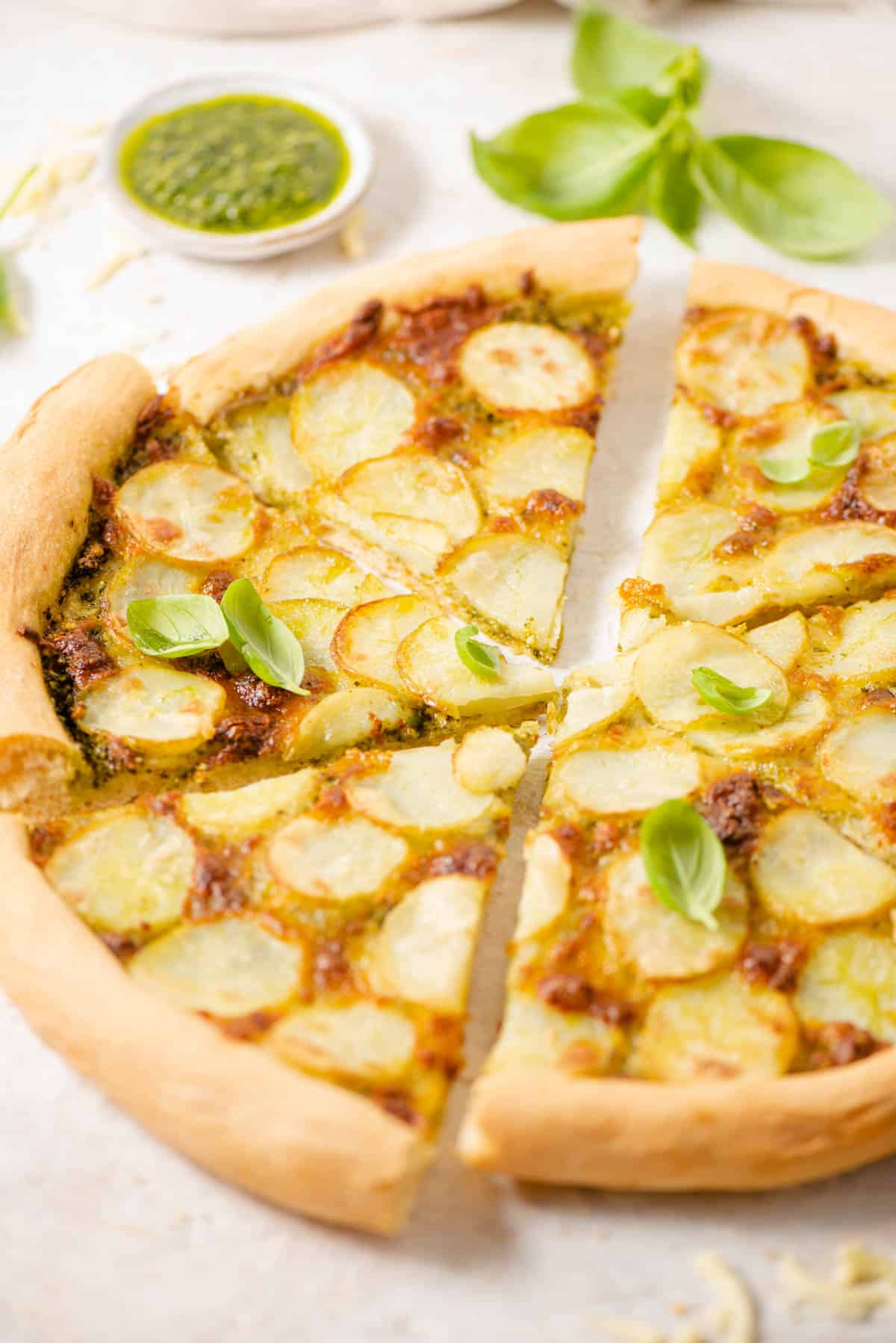 A side shot of a potato pizza cut into slices