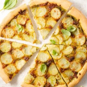 A close up of a potato pizza cut into slices