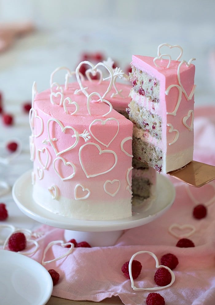 A photo of a pink ombré heart cake on a white marble table.