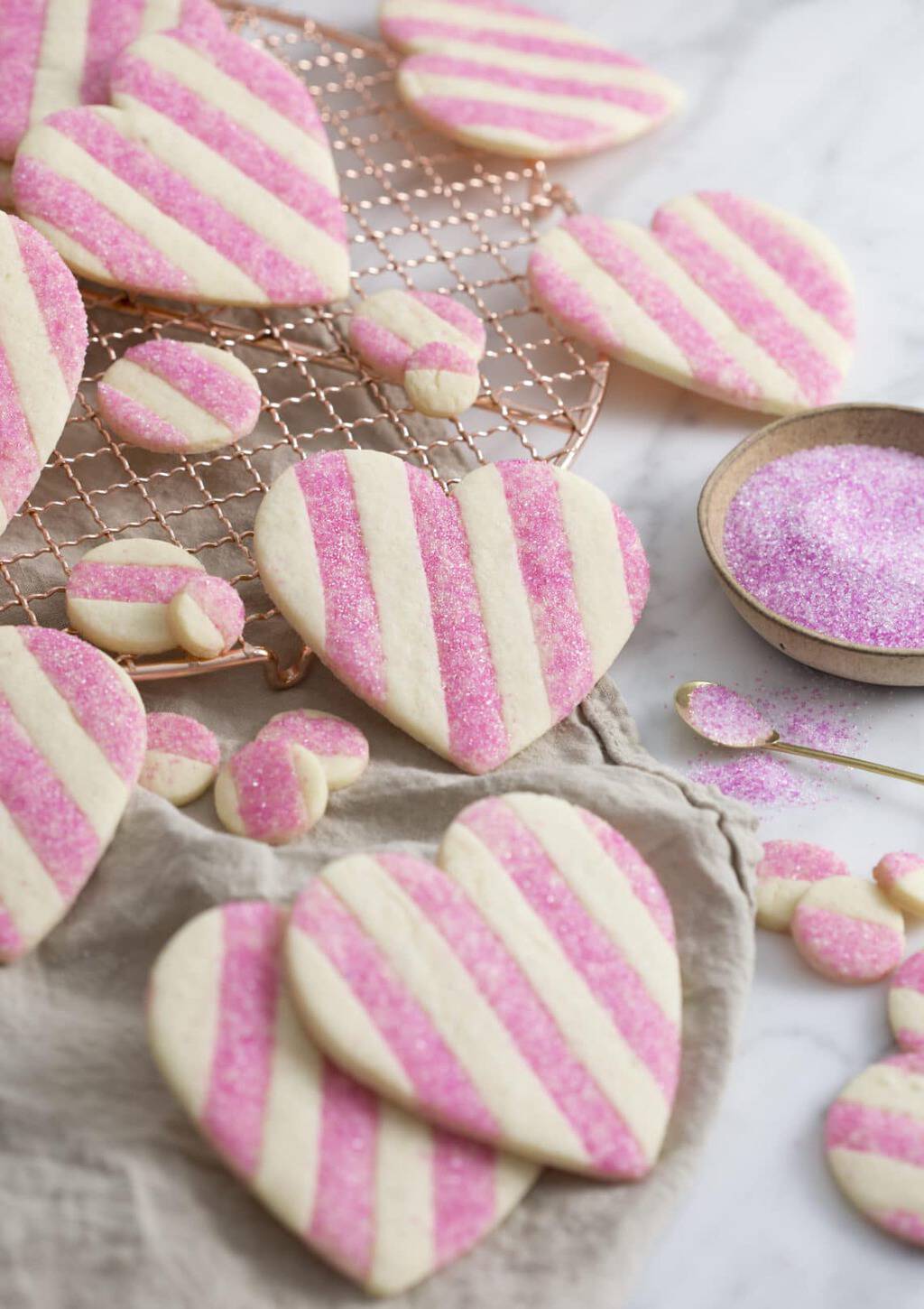 A photo showing a group of striped pink and white Valentine's Day Heart Cookies on a white marble surface
