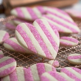 A close up photo of a pink and white striped valentine's day sugar cookie shaped like a heart.