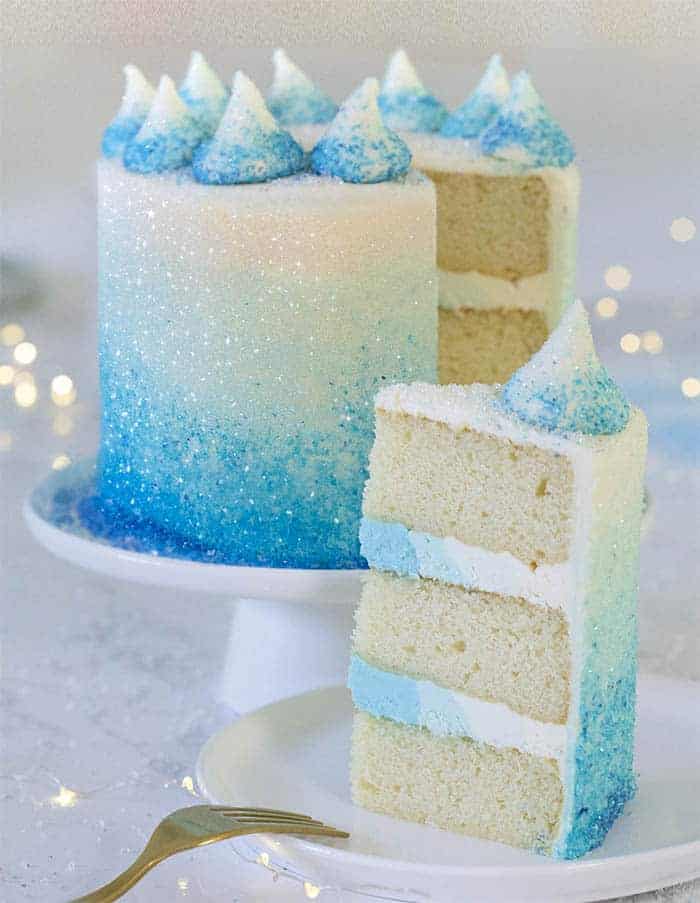 A winter wonderland cake with a piece in the foreground on a white plate.