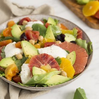 A photo of a colorful avocado salad with oranges and greens