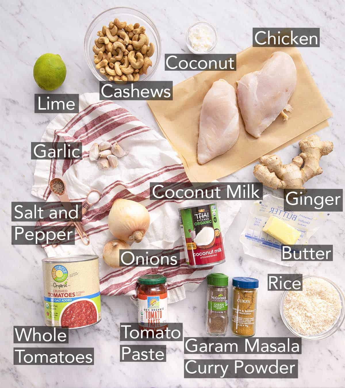 Ingredients to make butter chicken on a marble counter.