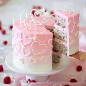 A pink ombré cake covered in white candy melt hearts.