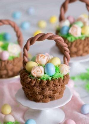 A cupcake that looks like an easter basket filled with flowers and eggs on a mini stand.