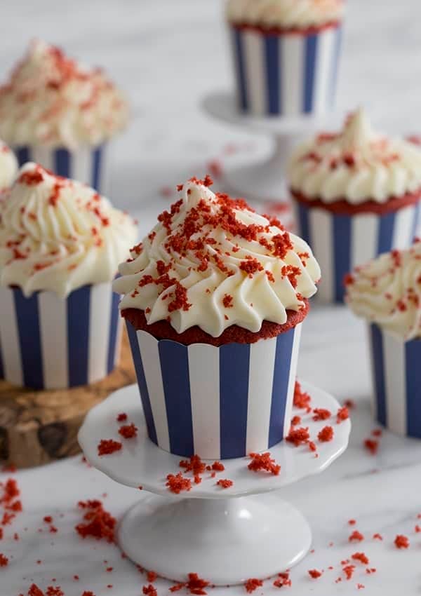 A photo of a group of red velvet cupcakes with a big dollop of cream cheese frosting.