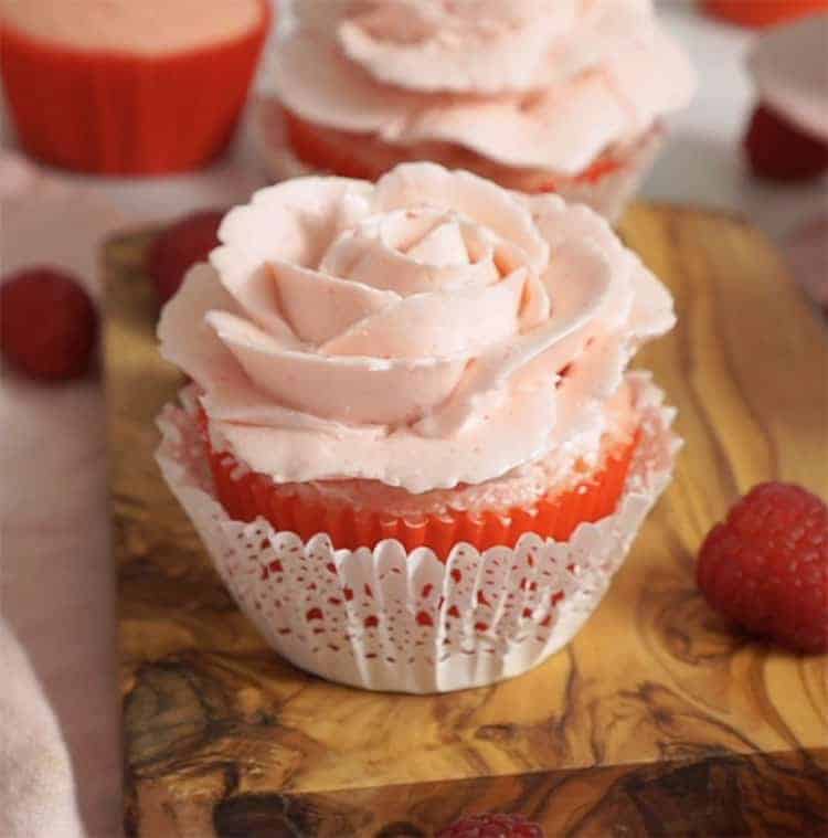A pink buttercream rose on a valentine cupcake.