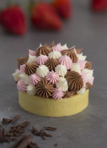 A photo of a Neapolitan tart with different sized dollops of Swiss meringue buttercream piped on top.