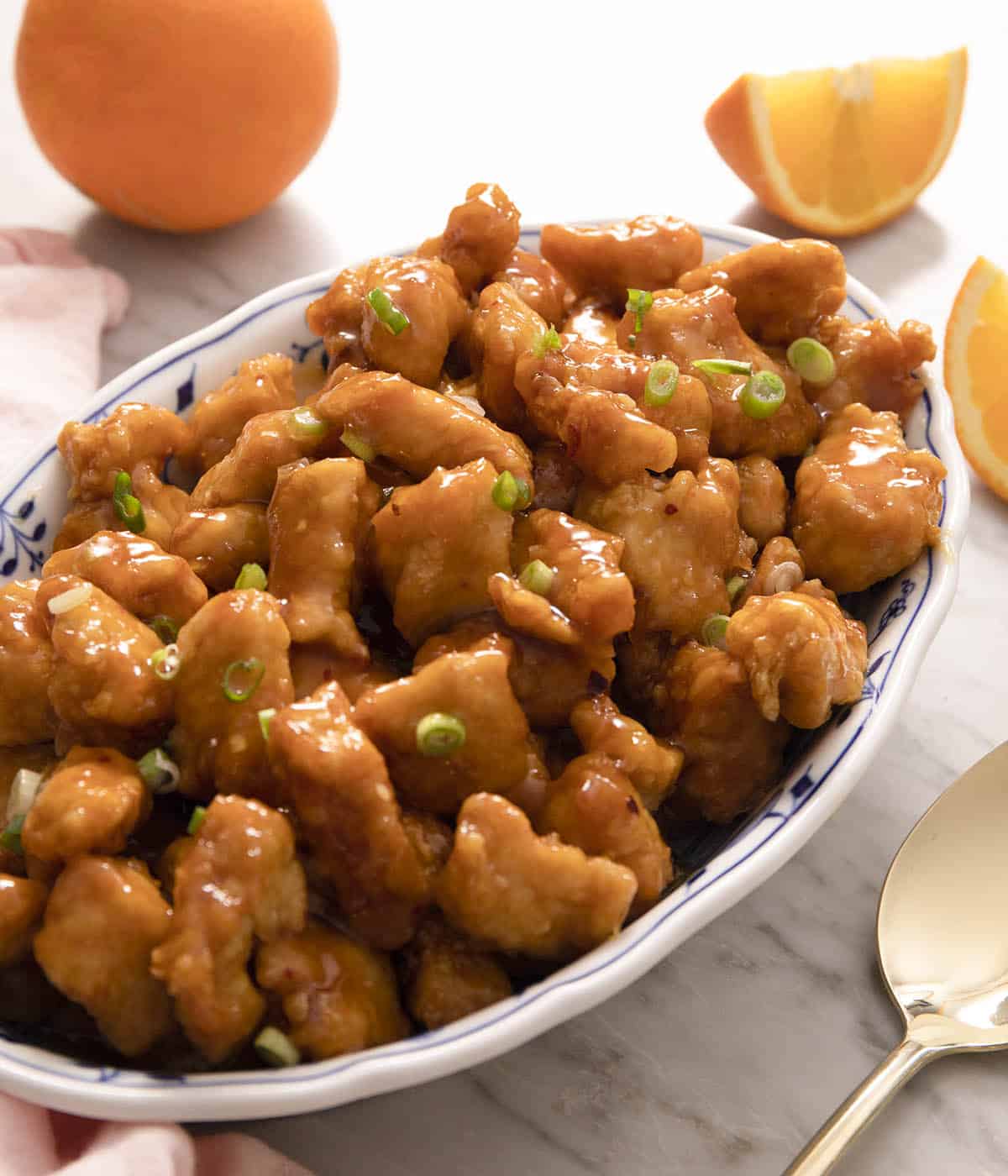 Orange chicken on a large plate topped with green onions