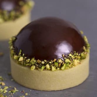 A chocolate and pistachio tart on a grey surface