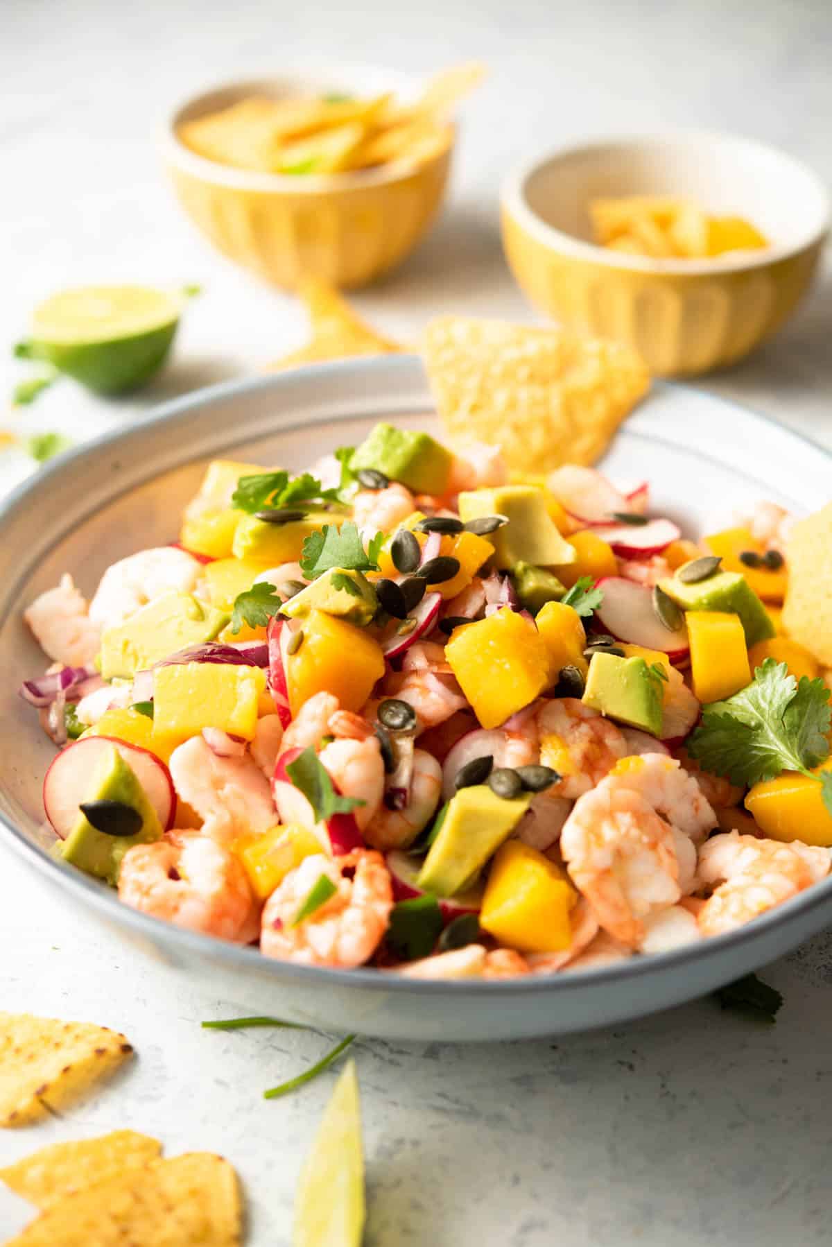 A side shot of shrimp ceviche in a blue bowl with mango and avocado