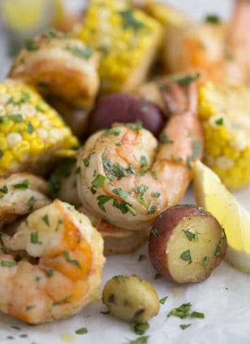 a closeup photo of a shrimp boil with potatoes, corn, and lemon