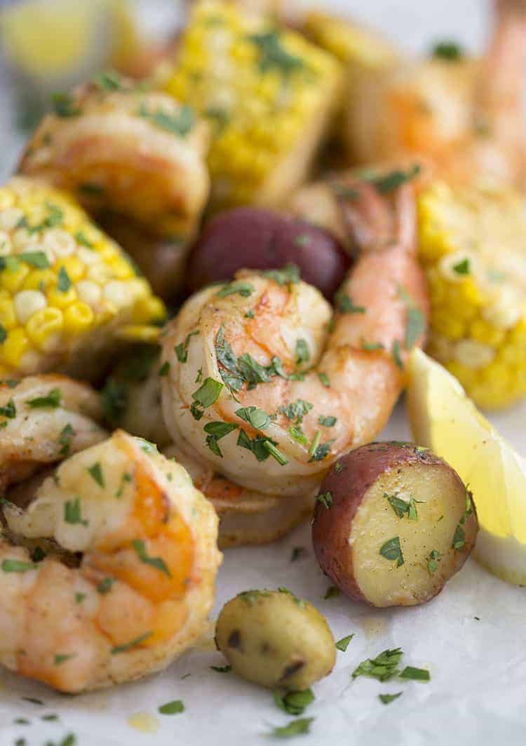 a closeup photo of a shrimp boil with potatoes, corn, and lemon