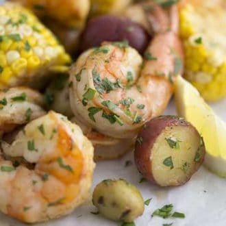 A closeup shot of a shrimp boil with baby potatoes, corn and lemon