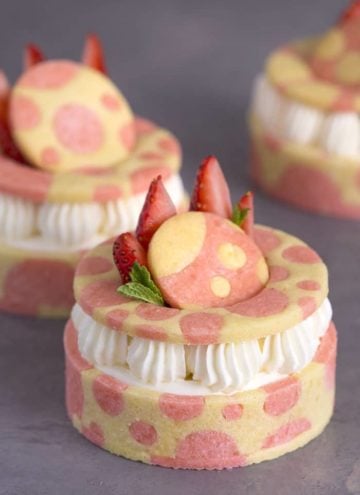 A photo showing a group of three strawberry tarts with pink dots on the pastry and fresh strawberries on top.